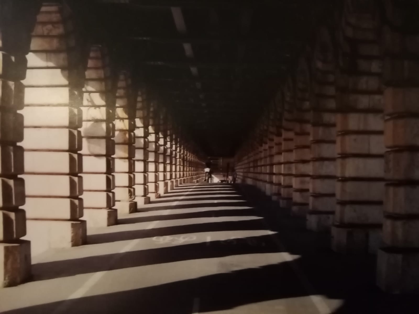 Passarela com arcos ao longo do caminho com sombreado refletido no chão